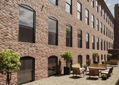 Courtyard outside of Westmoreland Lofts with potted trees, benches, and tables