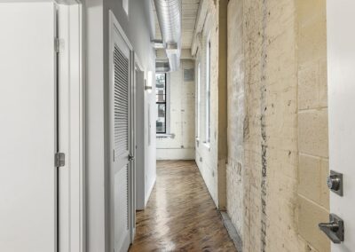 Hallway leading into living room of apartment with rustic brick wall.