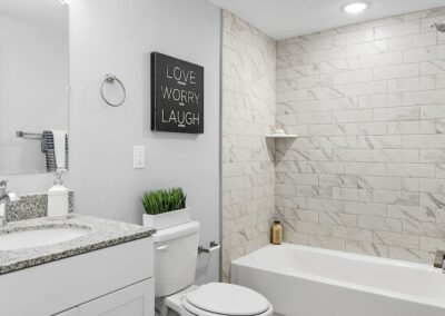 Bathroom with granite countertop, hanging mirror, and tiled shower walls.