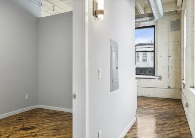 Hallway and empty room with hardwood flooring.