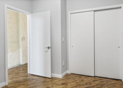 Bedroom entrance and view of white closet with sliding doors.