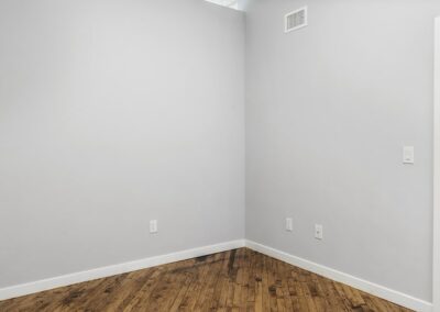 Empty bedroom with light grey walls and hardwood floors