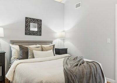 Bedroom with light grey walls, queen size bed, and throw blanket.