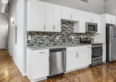 Kitchen with white cabinets, stainless steel appliances, and grey mosaic backsplash.