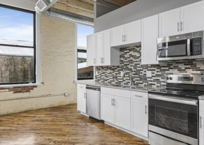 Kitchen with mosaic backsplash tiling, grey granite countertops, and stainless steel appliances.