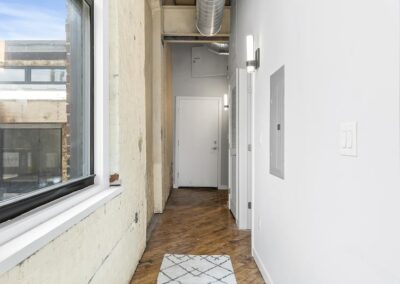 Hallway with window, rustic wall, and rug.