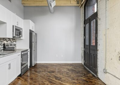 Open kitchen area with hardwood flooring and large windows made from renovated double doors.