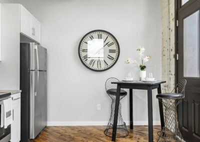 Dining area with black high table, high chairs, and large clock on wall.