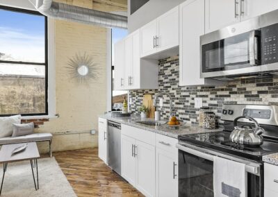 Kitchen with large windows, white cabinets, mosaic backsplash, and granite countertop.
