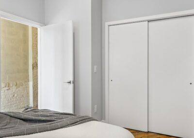 Bedroom with queen bed and view of white closet with sliding doors.