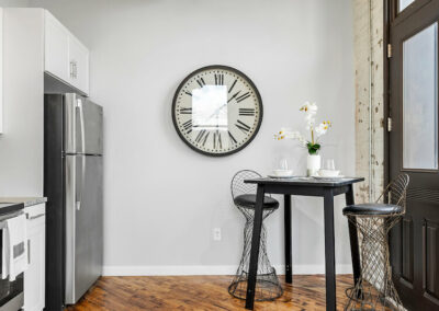 Seating area with chairs, large mounted clock, and hardwood floors.