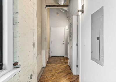 Hallway with rustic wall on one side leading to front door of apartment.