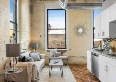 View of living room area, decorated and furnished, with a lot of natural lighting from windows.